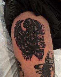 a bison tattoo on the leg of a man with an old style hat and other items