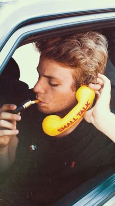 a man sitting in a car talking on a phone while holding an object to his ear