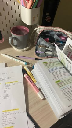 an open book sitting on top of a desk next to a cup and pencils