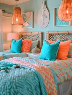 two beds in a room with blue and orange pillows on top of each bed,