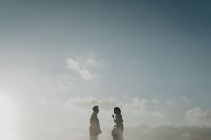 two people are standing in the sand on a sunny day