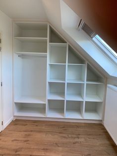 an empty room with white shelving in the corner and wood flooring on the other side