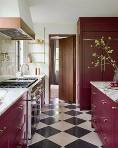 a kitchen with red cabinets and black and white checkered flooring on the walls