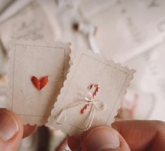 two pieces of paper with hearts on them are being held by someone's hand