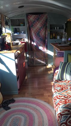 the inside of a camper with wood floors and colorful rugs on the floor