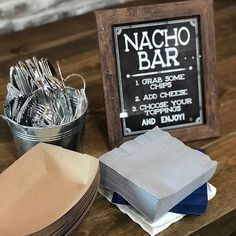 a table topped with lots of silverware next to a chalk board and metal bucket