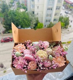 someone is holding a box full of fake flowers in their hand and looking out the window