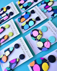 several different types of earrings are displayed on the blue tablecloth with white envelopes