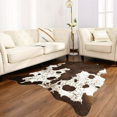 a living room with two white couches and a cowhide rug on the floor