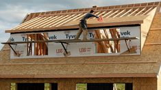 a man standing on the roof of a house under construction