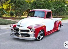 an old red and white truck parked on the street