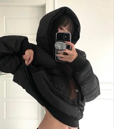 a woman taking a selfie in front of a mirror wearing a black hoodie