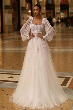 a woman in a white wedding dress standing on the floor with her hands on her hips