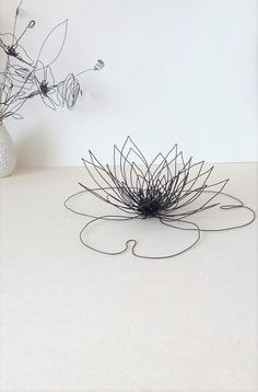 a vase with some flowers in it sitting on a white counter top next to a wire sculpture