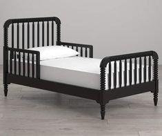 a small black bed with white sheets and pillows