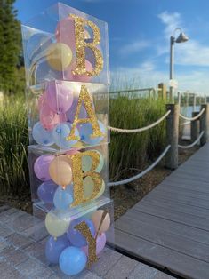 a clear acrylic box with balloons in it and the letters baa b