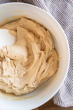 a white bowl filled with peanut butter on top of a wooden table next to a gray and white towel