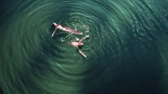 two people are swimming in the water with their backs turned to the same direction as they swim