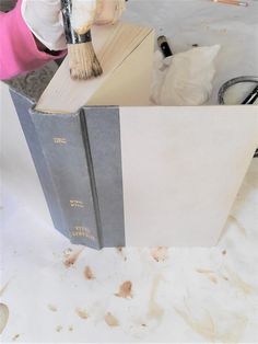 a person with a brush on top of a book in the process of painting it