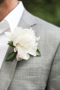 a man in a gray suit with a white flower on his lapel