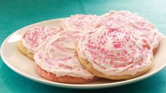 cookies with white frosting and pink sprinkles on a plate