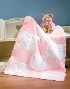 a teddy bear sitting on top of a pink blanket next to a white bench and wooden floor