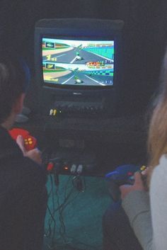 two people sitting in front of a tv playing a game on the nintendo wii console