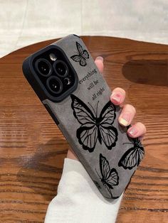 a woman holding up her phone case with butterflies on it