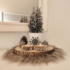 two candles are sitting on a tree stump with snowflakes and pine cones in the center