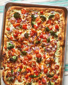 a square pizza with tomatoes, broccoli and onions