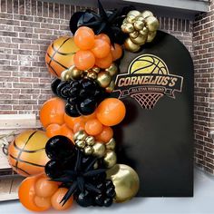 an orange and black balloon arch with basketballs on it