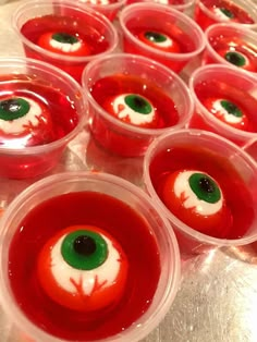 several plastic cups filled with red liquid and green eyeballs