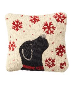 a knitted pillow with a black dog wearing a red collar and snowflakes on it