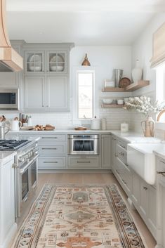 a kitchen with an area rug in front of the stove and sink, along with white cabinets