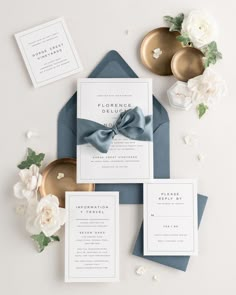 the wedding stationery is laid out on top of blue envelopes and white flowers