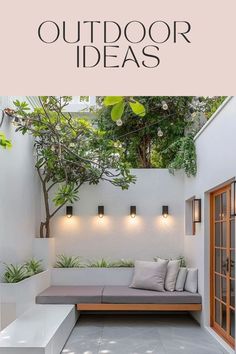 an outdoor seating area with plants and lights on the wall, next to a white bench