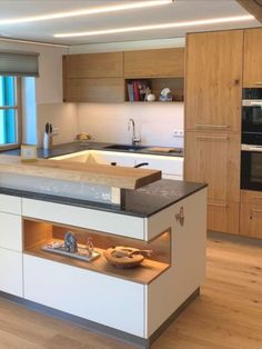 a kitchen with an island, sink and oven in it's center area that is lit up by recessed lighting