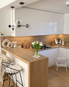 a kitchen with white cabinets and wooden counter tops, along with two stools in front of the island