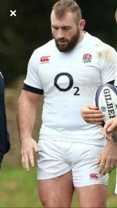 two men are talking to each other while holding a rugby ball