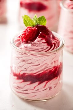 a jar filled with raspberry cheesecake and topped with a fresh mint leaf