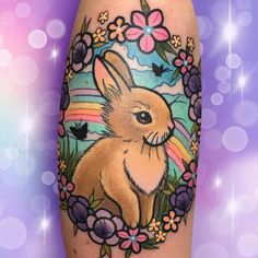 a rabbit tattoo on the leg with flowers and butterflies around it, surrounded by stars