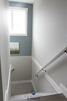 an empty hallway with white painted walls and stairs leading up to a window above the door