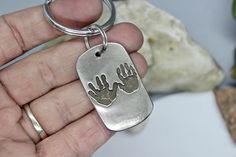 a hand holding a dog tag with two hands on it and another hand that has been stamped onto