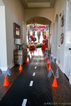 an entry way decorated with orange and black cones, checkered flags, and balloons