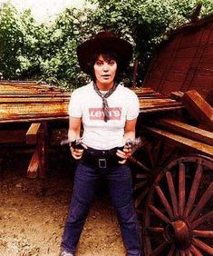 a woman standing in front of an old wagon