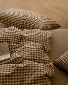 a brown and white checkered comforter sitting on top of a couch next to pillows