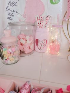 pink and white candies are in glass containers on the counter next to other candy