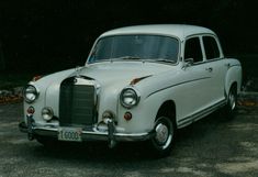 an old white car parked in a parking lot