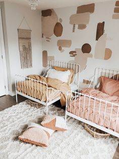 two twin beds in a bedroom with pink and gold decor on the wall behind them