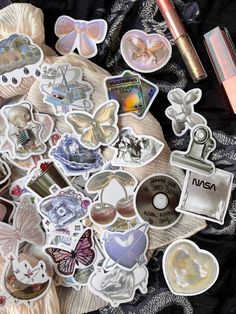 many different stickers are laying on top of a cloth with other items around them